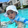 baby, child, swimming_pool, water, hat, sun_hat, blue, swimsuit, shark_pattern, person, outdoor, summer, water_activity, holding, face, headwear, recreation, skin, cute, expression