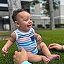 Zakkai is registered to the contest to win money with this photo: baby, child, smiling, grass, outdoor, tank_top, striped_clothing, hands, supporting, happy, nature, trees, building, residential, blurred_background, feet, sitting, cute, portrait, daylight