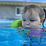 Paisley is registered to the contest to win money with this photo: child, pool, water, face, wet_hair, blue_sky, building, outdoor, summer, swimming, young_child, puffy_cheeks, reflection, closeup, playful, water_surface, daytime, casual, fun, relaxation