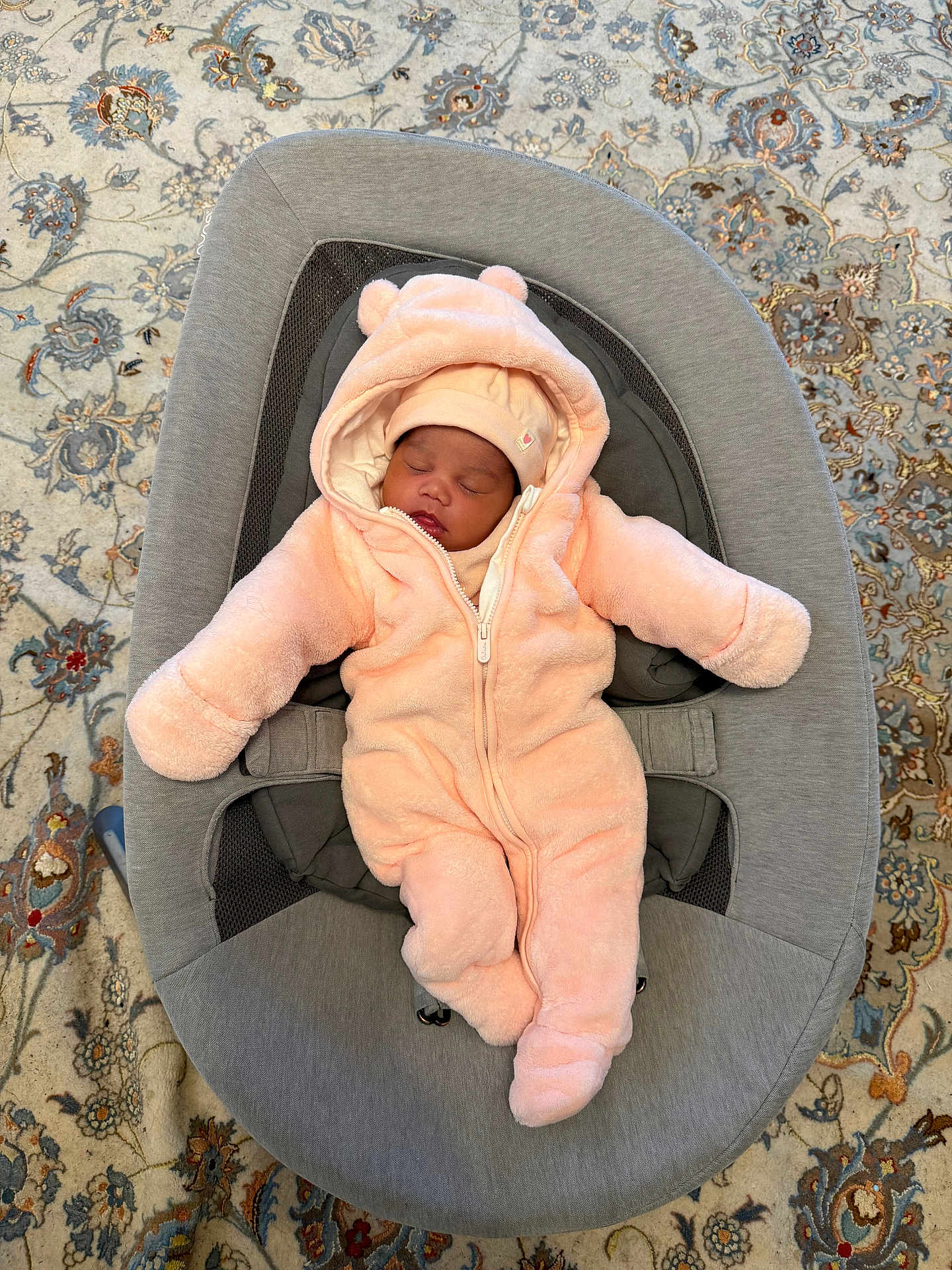 Névaëh participe au concours pour gagner de l'argent avec cette photo : baby, sleeping, onesie, pink, bear_ears, baby_rocker, gray, carpet, patterned, indoor, cozy, child, infant, soft, clothing, cute, resting, face, hat, comfort