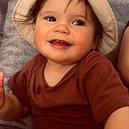 Malone a rejoint le concours — aidez-le/la à gagner de superbes lots ! toddler, child, smiling, hat, bucket_hat, brown_shirt, toy_piano, colorful, indoor, couch, happy, playful, cute, infant, face, person, seated, furniture, home, young_child