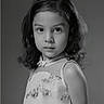 child, girl, portrait, black_and_white, dress, curly_hair, flower_embroidery, serious_expression, studio, monochrome, youth, innocence, soft_lighting, fashion, elegant, looking_at_camera, isolated, childhood, cute, young