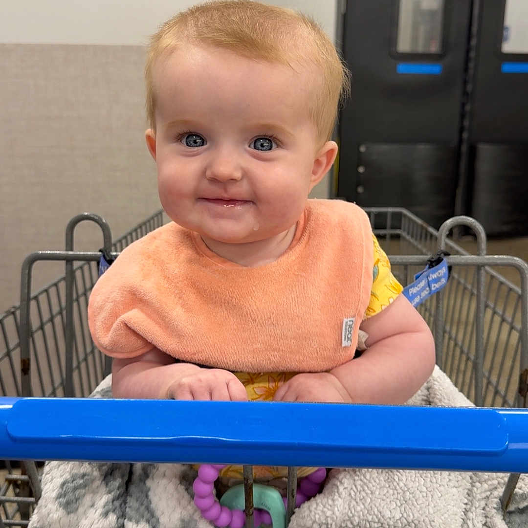 Renley joined the competition — help win amazing prizes! baby, bib, blanket, blue_eyes, child, clothing, cute, door, exit_sign, face, hand, indoor, infant, metal, person, shopping, shopping_cart, smiling, teether, toy