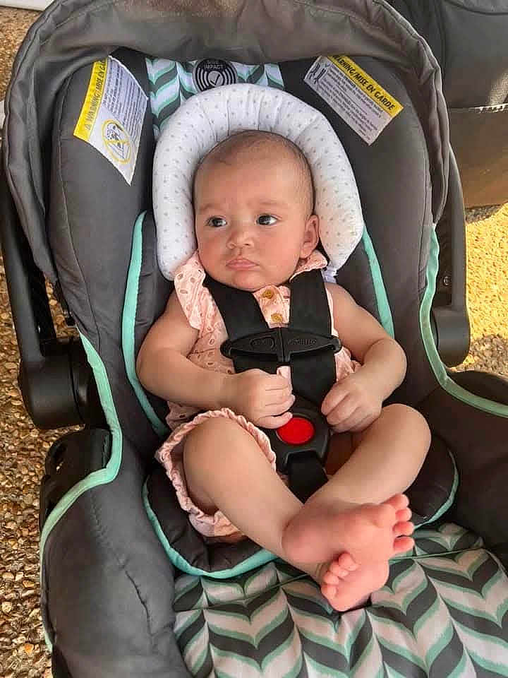 Dani is registered to the contest to win money with this photo: baby, car_seat, infant, child, safety_straps, cushion, pink_clothing, foot, hand, head_support, outdoor, seat, fabric, pattern, skin, person, cute, small, resting, comfortable