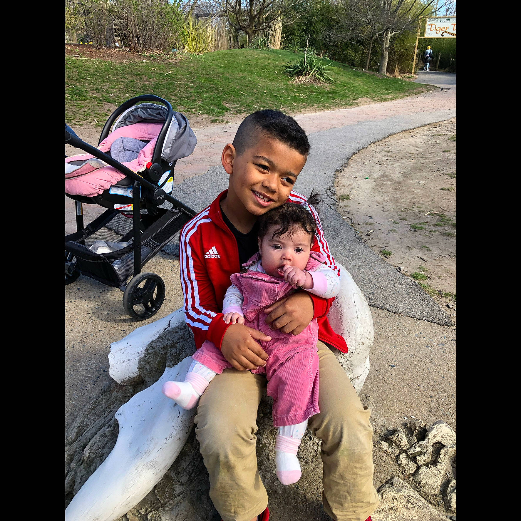 Dj is registered to the contest to win money with this photo: baby, baby_carriage, baby_products, child, cool, fun, grass, happy, joy, lap, leisure, mammal, person, plant, product, public_space, sitting, smile, toddler, toy