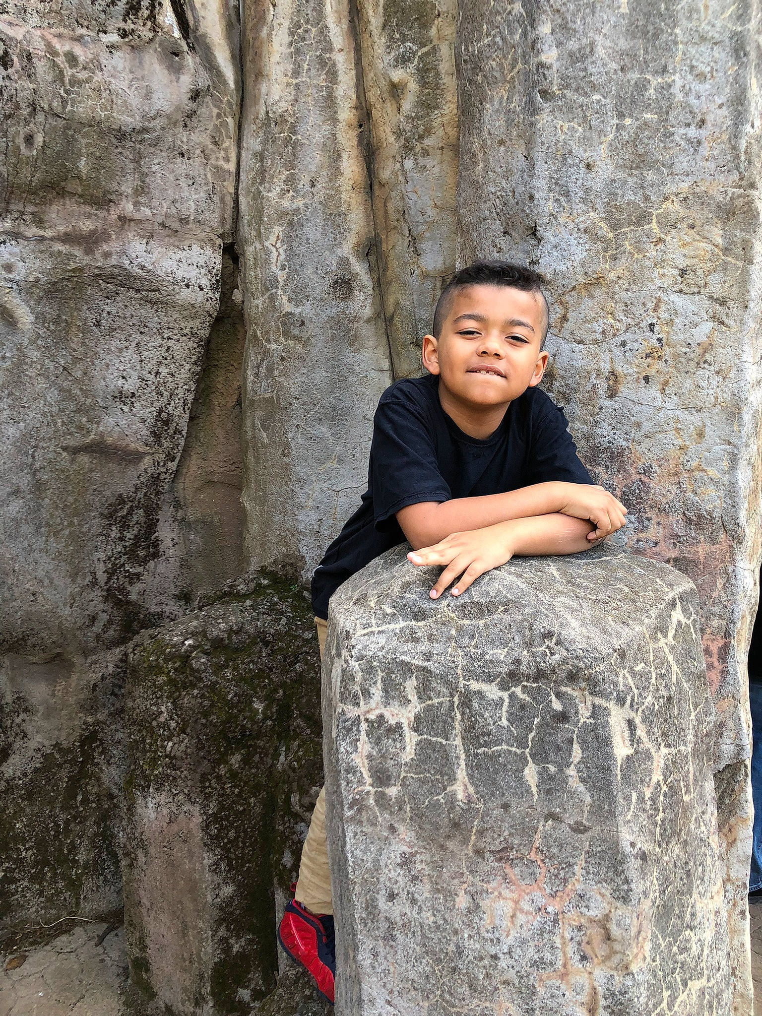 Dj is registered to the contest to win money with this photo: bedrock, child, concrete, eye, fun, happy, landscape, leisure, outcrop, person, recreation, rock, sitting, smile, stone_wall, temple, toddler, travel, trunk, vacation