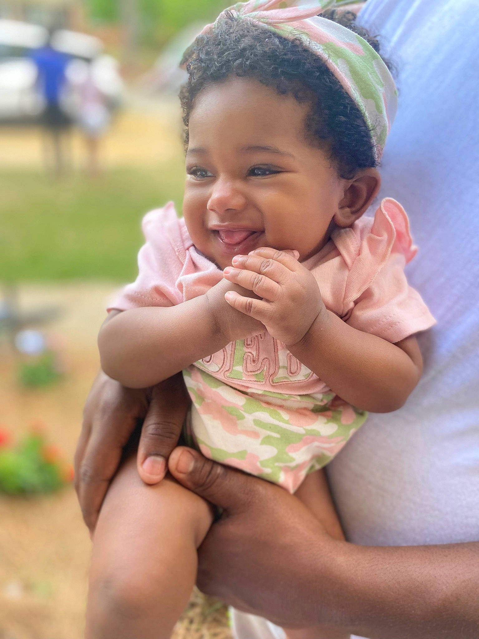 Kamilah is registered to the contest to win money with this photo: baby, baby_toddler_clothing, cheek, child, chin, finger, fun, gesture, grass, happy, leisure, lip, mouth, nose, people_in_nature, person, pink, skin, smile, thumb