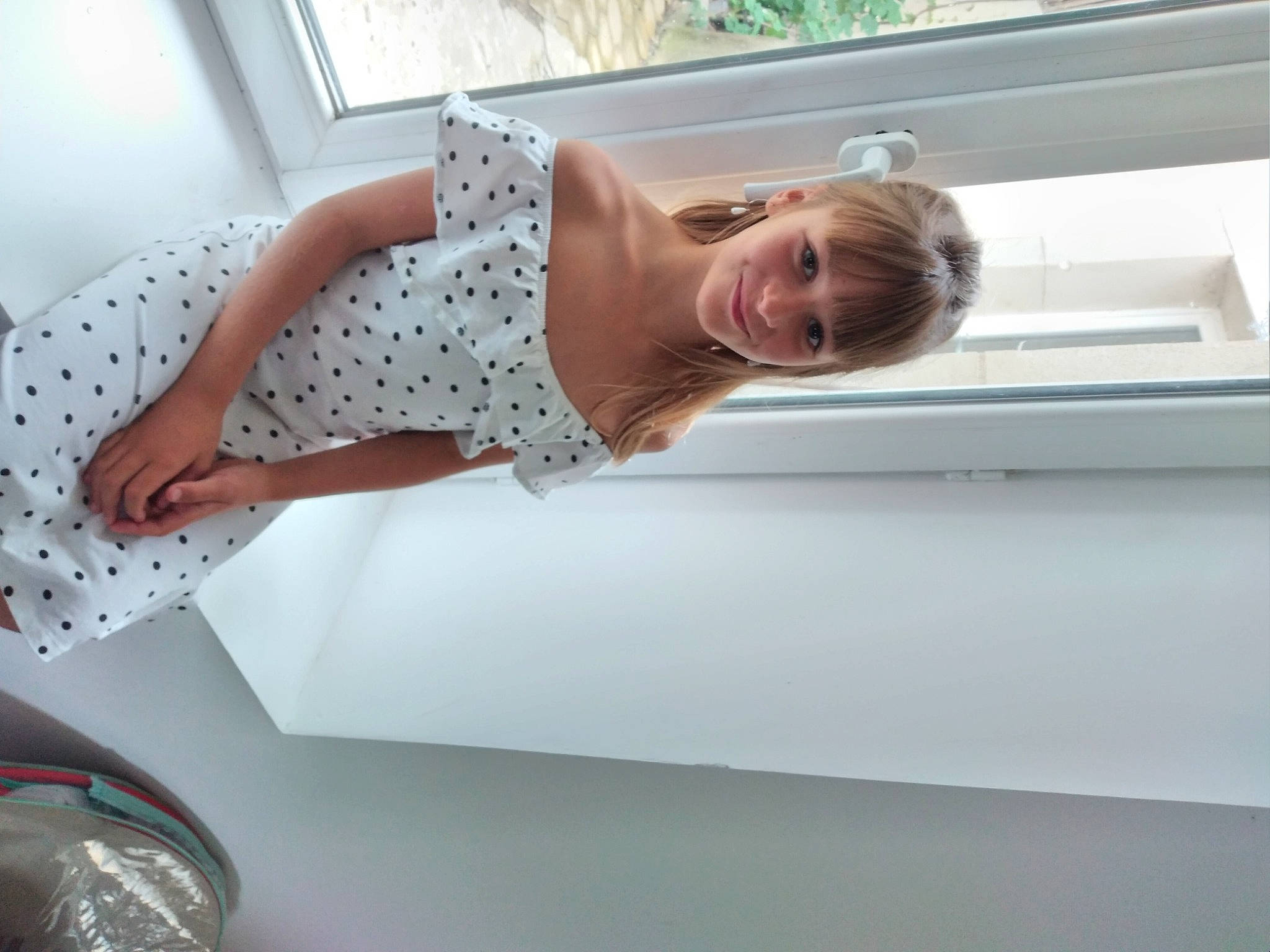 Maëlys a rejoint le concours — aidez-le/la à gagner de superbes lots ! automotive_lighting, automotive_tail_brake_light, bumper, comfort, dress, elbow, fun, hood, human_leg, joy, knee, pattern, person, room, smile, thigh, toddler, vehicle_door, waist, white