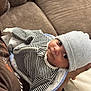 arm, baby, blanket, casual, closeup, couch, cozy, cute, face, hat, headwear, holding, indoor, infant, newborn, person, resting, soft, striped_clothing, toddler