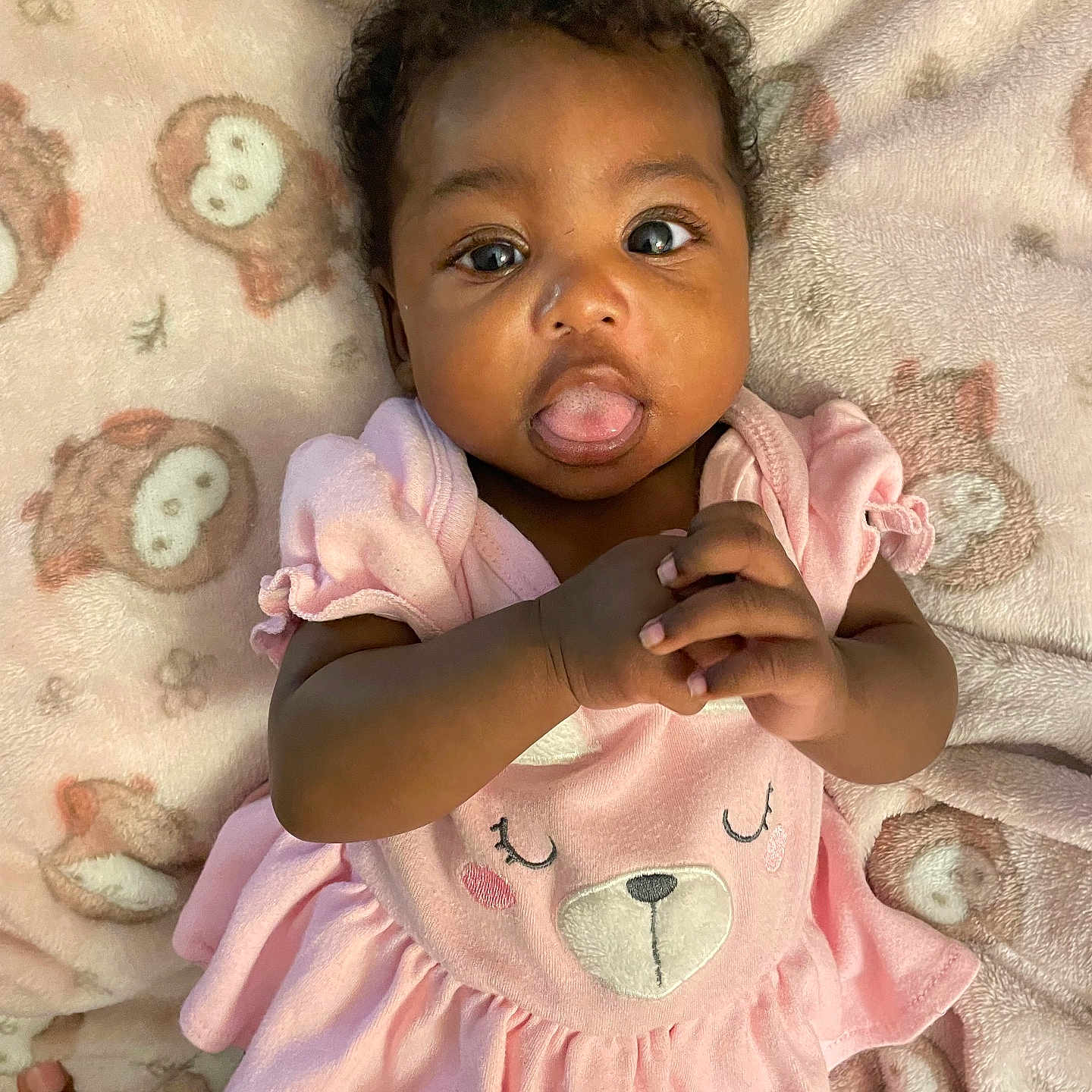 Azyla joined the competition — help win amazing prizes! baby, infant, child, pink_dress, bear_face, blanket, owl_pattern, curly_hair, tongue_out, hands_clasped, cute, playful, lying_down, soft_texture, indoors, portrait, smiling_face, adorable, young_child, cozy