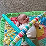 Emmett joined the competition — help win amazing prizes! baby, play_mat, toy, carpet, infant, smiling, colorful, striped, soft_toy, floor, child, cute, lying_down, happy, indoors, person, green, yellow, blue, red