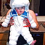 baby, costume, stay_puft, marshmallow_man, kitchen, person, adult_hands, child, holiday, funny, cute, indoor, cabinet, dishwasher, floor, curtains, countertop, carpet, face, clothing