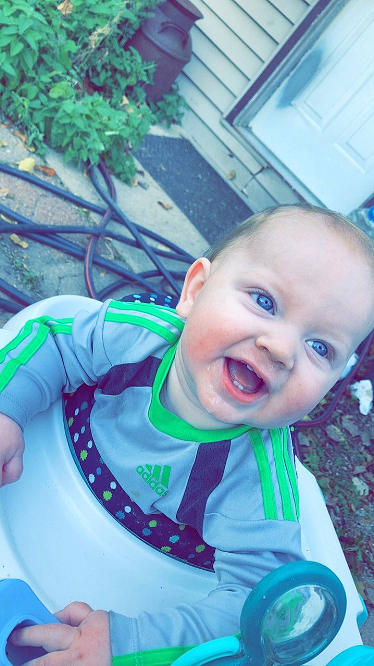 Ryder is registered to the contest to win money with this photo: baby, baby_laughing, baby_products, baby_toddler_clothing, blue, cheek, child, cool, electric_blue, fun, grass, happy, leisure, person, plant, play, product, recreation, sitting, smile