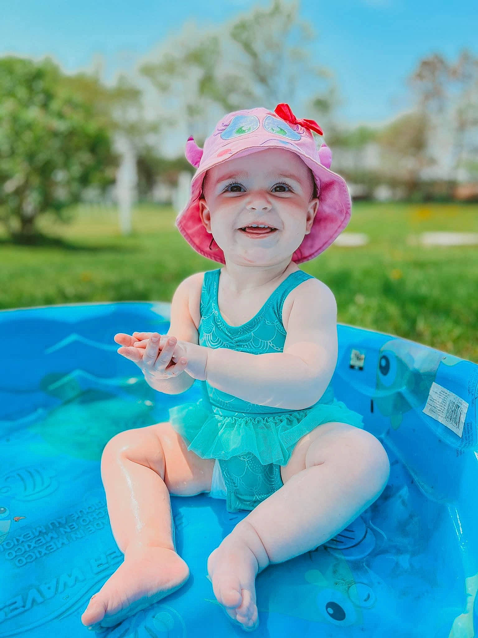 Adeline joined the competition — help win amazing prizes! aqua, azure, baby, baby_toddler_clothing, cap, child, electric_blue, facial_expression, fun, grass, happy, hat, headwear, joy, leisure, person, pink, plant, recreation, sky