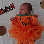 Isla-Rose joined the competition — help win amazing prizes! baby, infant, halloween, orange_clothing, pumpkin_costume, tulle_skirt, blanket, face, cute, holiday, festive, lying_down, costume, child, celebration, smile, decoration, holiday_theme, person, indoors