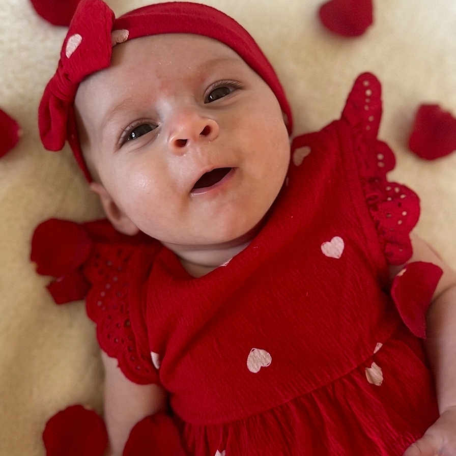 Giulia a rejoint le concours — aidez-le/la à gagner de superbes lots ! baby, infant, red_dress, headband, heart_pattern, rose_petals, blanket, lying_down, portrait, cute, smiling, happy, child, closeup, soft_texture, adorable, young_child, celebration, festive, warm