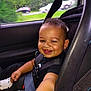 Zakarian is registered to the contest to win money with this photo: child, toddler, car_seat, smiling, happy, seatbelt, black_clothing, car_interior, window, greenery, trees, road, daylight, vehicle, baby, cute, portrait, person, safety, seat