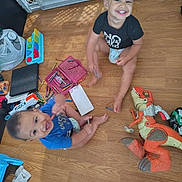 Zakarian is registered to the contest to win money with this photo: toddler, child, floor, crayons, toys, dinosaur_toy, smiling, playtime, diaper, wood_floor, marker, pacifier, baby, happy, indoor, plastic_toy, colorful, messy, fun, clothing