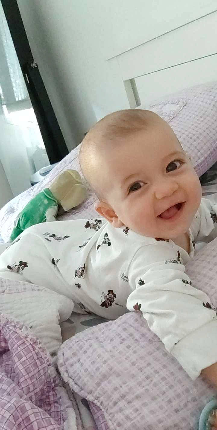 Ilyana a rejoint le concours — aidez-le/la à gagner de superbes lots ! baby, baby_laughing, baby_products, baby_safety, baby_toddler_clothing, bedding, cheek, child, collar, comfort, eye, flooring, happy, joy, linens, person, room, sitting, skin, sleeve