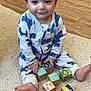 toddler, child, baby, pajamas, dinosaur_print, carpet, wooden_blocks, toy, floor, play_mat, feet, hand, indoor, person, smiling, cute, play, home, infant, happy