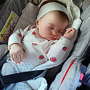 Leonida Ana participe au concours pour gagner de l'argent avec cette photo : baby, sleeping, car_seat, headband, white_clothing, ladybug_print, infant, child, peaceful, cute, soft_lighting, straps, fabric, resting, indoors, portrait, closeup, cozy, toddler, seatbelt