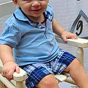 Huntley joined the competition — help win amazing prizes! toddler, child, smiling, blue_shirt, plaid_shorts, white_shoes, chair, wooden_chair, indoor, height_chart, happy, portrait, cute, baby, shorts, footwear, sitting, person, casual_clothing, light_hair