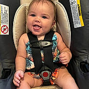 Mackenzie joined the competition — help win amazing prizes! baby, child, car_seat, smiling, tongue_out, safety_harness, colorful_clothing, tropical_pattern, happy, infant, cute, person, seat, straps, indoors, portrait, small_hands, legs, hair_tie, closeup
