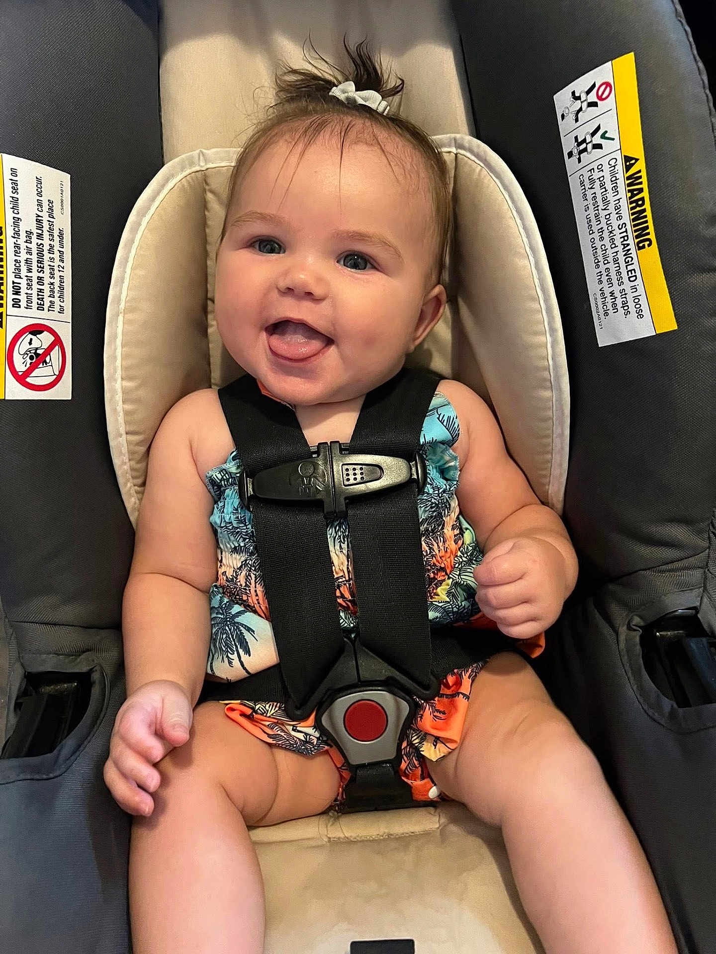 Mackenzie joined the competition — help win amazing prizes! baby, child, car_seat, smiling, tongue_out, safety_harness, colorful_clothing, tropical_pattern, happy, infant, cute, person, seat, straps, indoors, portrait, small_hands, legs, hair_tie, closeup