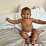 baby, smiling, diaper, bed, pillow, blanket, happy, child, infant, cute, arms_outstretched, indoor, skin, face, toes, sitting, room, cozy, neutral_colors, expression