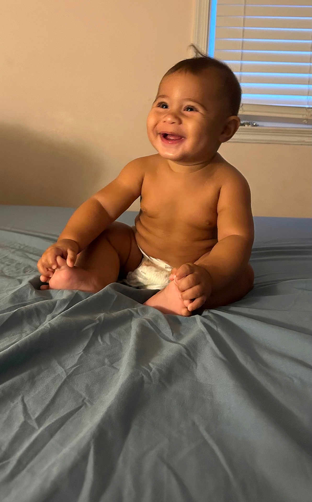 Shiye joined the competition — help win amazing prizes! baby, child, smiling, diaper, bed, sheet, indoor, window, window_blinds, skin, happy, cute, infant, person, bare_chest, sitting, young, room, light, portrait