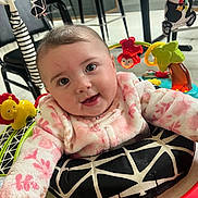 Tinley is registered to the contest to win money with this photo: baby, infant, smiling, eyes, face, pink_clothing, onesie, play_center, toy, lion_toy, panda_toy, activity_center, seat_cushion, indoor, floor, highchair_like, cheek, hair, hand, cute
