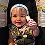 baby, child, smiling, car_seat, seatbelt, beanie, infant, cute, holding_object, pink, bottle, floral_pattern, happy, portrait, indoor, person, young_child, closeup, headwear, safety