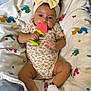 baby, child, headband, bow, teether, blanket, sock, floor, infant, cute, lying_down, colorful, patterned_clothing, toy, indoor, portrait, young_child, playful, comfort, happy