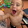 Kayden joined the competition — help win amazing prizes! arm, bare_chested, chair, child, closeup, face, floor, foot, green_basket, happy, laughing, leg, outdoor, patio, person, playtime, smiling, tattoo, toddler, toys