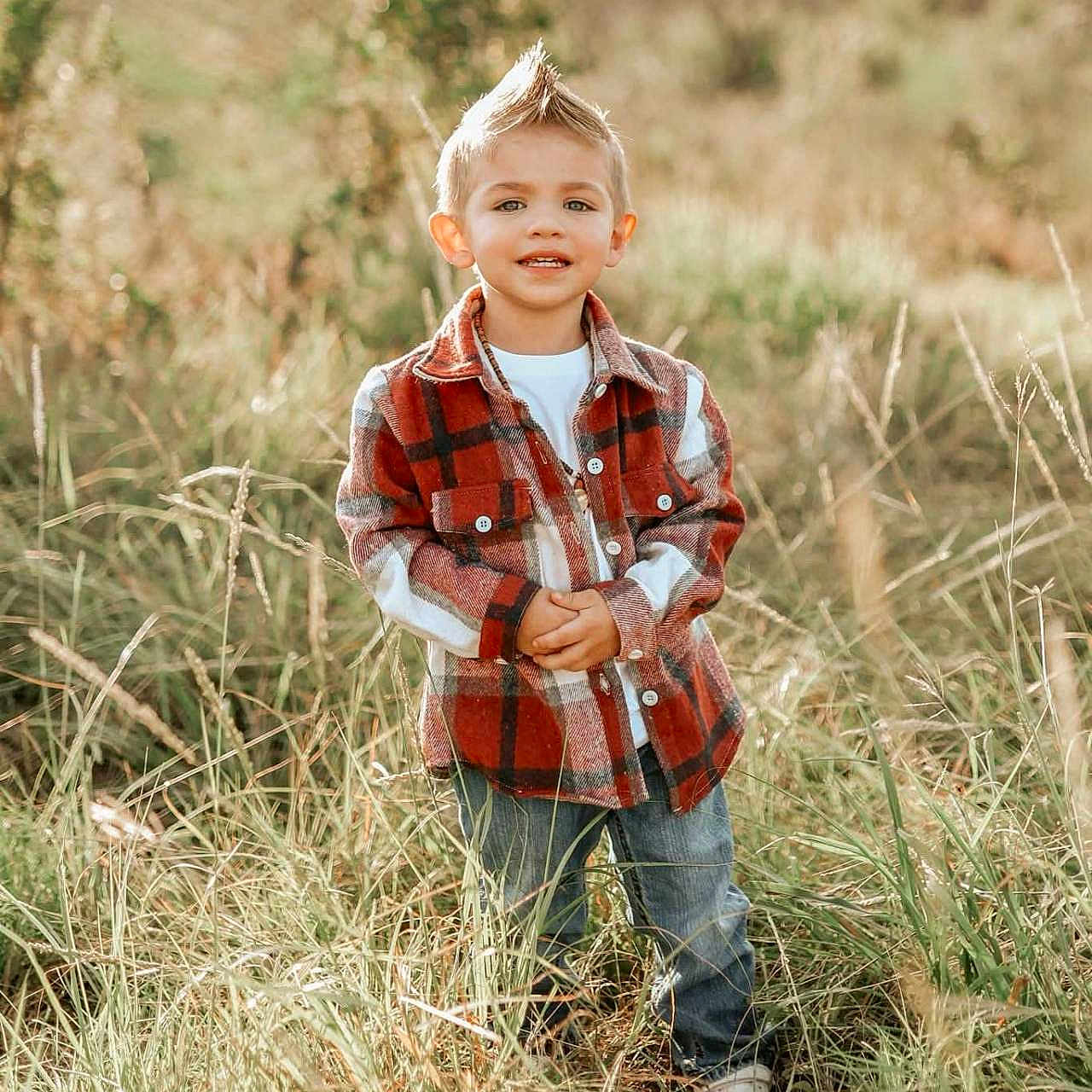 Juan Leo is registered to the contest to win money with this photo: boy, casual_clothing, child, daytime, field, grass, hairstyle, happy, jeans, mohawk, nature, outdoor, person, plaid_jacket, portrait, smiling, standing, sunlight, white_shirt, young