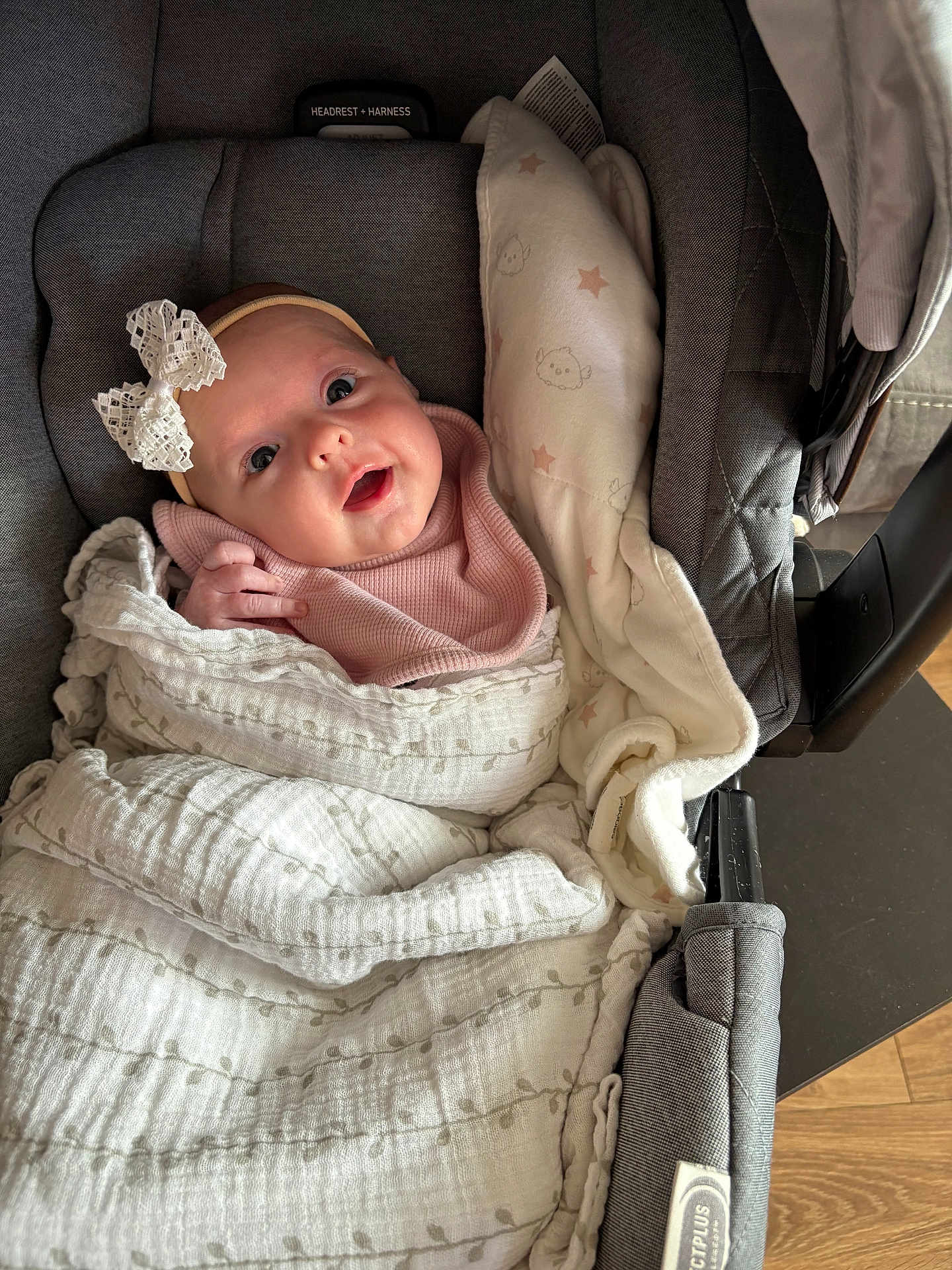 Aria joined the competition — help win amazing prizes! baby, infant, car_seat, blanket, bow, pink_clothing, face, headband, wrapped, cute, child, soft_texture, indoor, smiling, toddler, newborn, person, cozy, happy, closeup