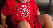 Izael is registered to the contest to win money with this photo: child, toddler, red_shirt, gold_chains, smile, leather_couch, sitting, casual, confident, indoor, short_hair, footwear, cute, portrait, young_child, positive_message, happy, fashion, person, relaxed
