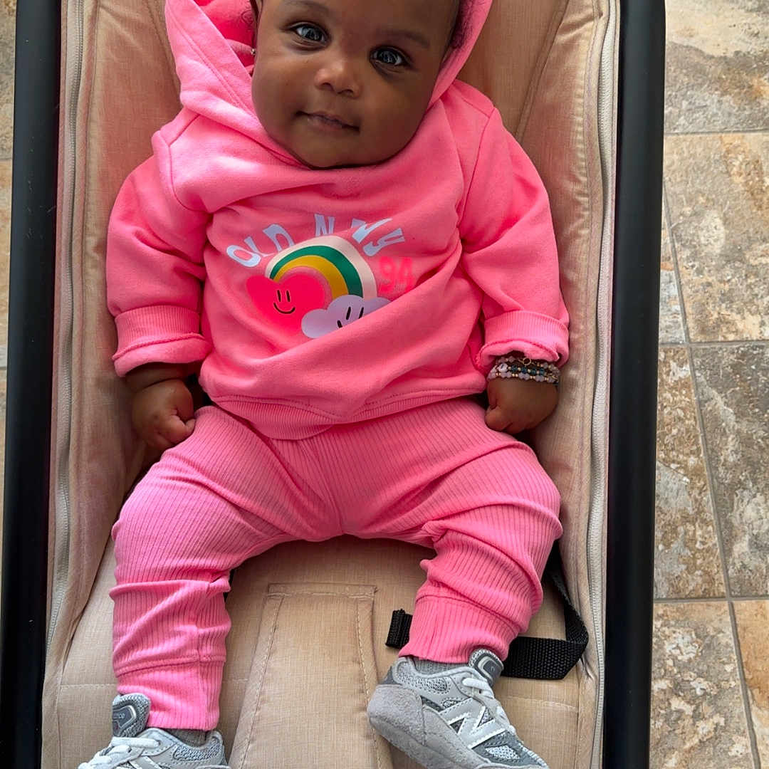 Kamari is registered to the contest to win money with this photo: baby, chair, clothing, coat, couch, face, footwear, furniture, head, jacket, knitwear, pants, person, photography, portrait, runningshoe, shoe, sitting, sneaker, sweater
