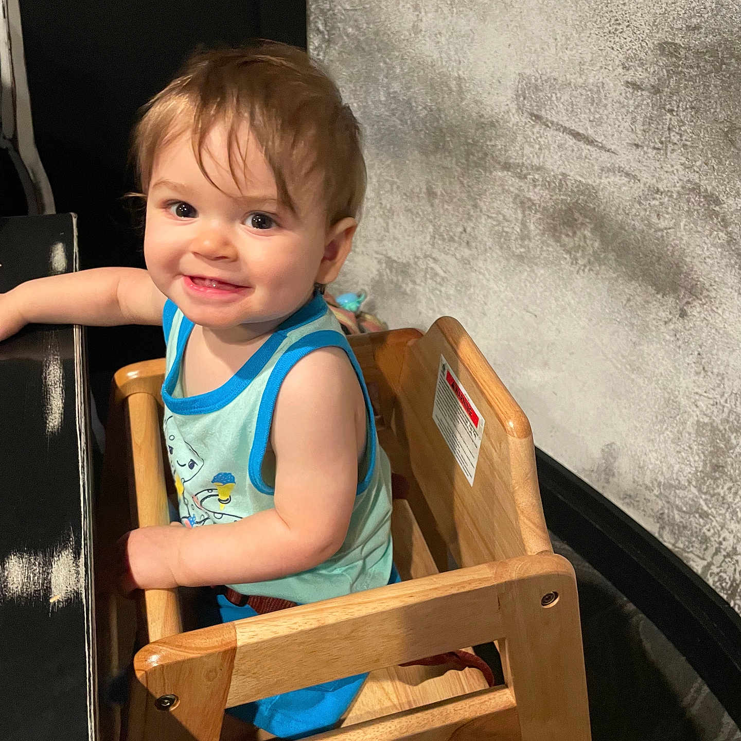 Grayson is registered to the contest to win money with this photo: baby, bodypart, chair, clothing, dress, face, finger, furniture, hand, happy, head, highchair, person, photography, plywood, portrait, sitting, smile, t_shirt, wood