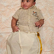 Daniel joined the competition — help win amazing prizes! baby, child, traditional_clothing, face, portrait, infant, lying_down, curious_expression, patterned_background, cute, young_child, indoors, textile, gold_trim, short_sleeves, buttoned_shirt, small_hands, head, soft_lighting, cultural