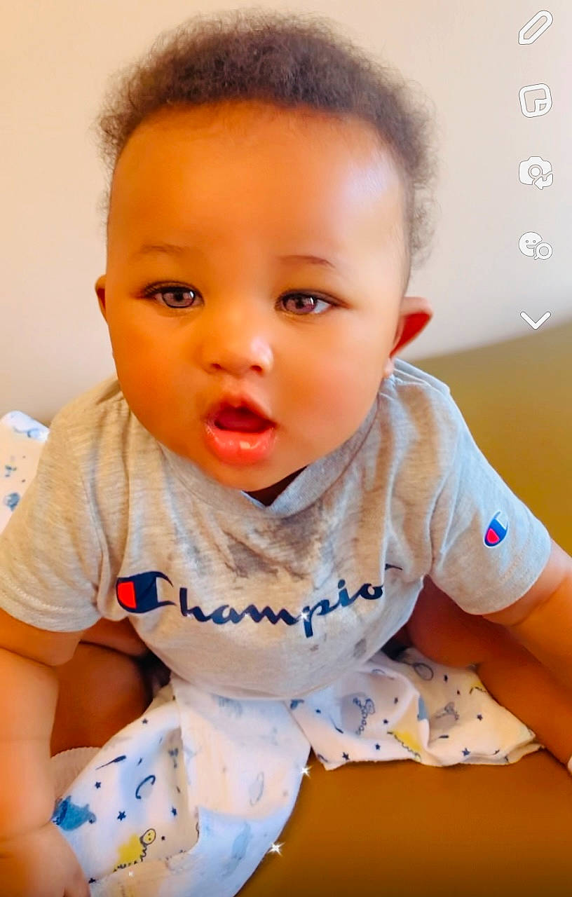 Nori is registered to the contest to win money with this photo: baby, baby_toddler_clothing, cheek, child, elbow, eye, eyelash, flooring, fun, happy, iris, lip, mouth, neck, nose, person, sitting, skin, sleeve, t_shirt