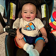 Ethan Mori is registered to the contest to win money with this photo: baby, smiling, car_seat, infant, child, happy, clothing, socks, indoor, person, face, cute, seat, comfort, rosy_cheeks, shorts, tshirt, toy, colorful, cozy