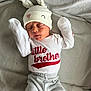 Lucas is registered to the contest to win money with this photo: baby, newborn, infant, hat, bunny_ears, clothing, shirt, pants, blanket, sleeping, cute, child, red_text, white_clothing, gray_pants, red_socks, soft_texture, portrait, lying_down, peaceful