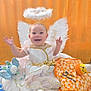 Stella is registered to the contest to win money with this photo: angel_costume, baby, blanket, celebration, child, costume, cute, festive, halloween, halo, happy, holiday, infant, orange_background, plush, portrait, sitting, smiling, toy, wings