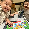 child, smiling, table, game, board_game, indoor, furniture, chair, couch, toy, happy, person, playing, colorful, face, young, kids, family, casual, portrait