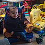 child, toddler, smile, indoor, toy, chair, playroom, colorful, furniture, carpet, casual_clothing, happy, young_child, living_room, plastic_toy, footwear_off, decor, small_table, remote_control, stuffed_toy