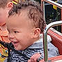 Cameron is registered to the contest to win money with this photo: child, toddler, curly_hair, laughing, seat, safety_strap, ride, hand, clothing, patterned_sweater, face, ear, outdoor, playground, metal_rail, joy, happiness, person, smile, fun