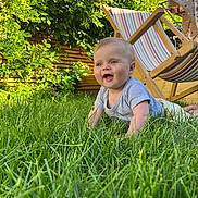 Gabin a rejoint le concours — aidez-le/la à gagner de superbes lots ! baby, grass, outdoor, smiling, child, deck_chair, greenery, sunlight, happy, nature, garden, person, summer, wooden_furniture, toddler, blue_eyes, short_sleeves, playful, crawling, daylight