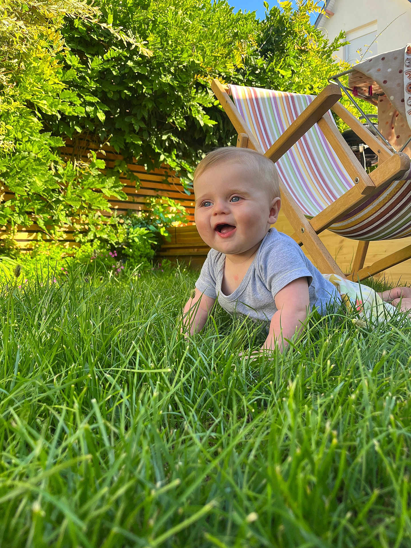 Gabin a rejoint le concours — aidez-le/la à gagner de superbes lots ! baby, grass, outdoor, smiling, child, deck_chair, greenery, sunlight, happy, nature, garden, person, summer, wooden_furniture, toddler, blue_eyes, short_sleeves, playful, crawling, daylight