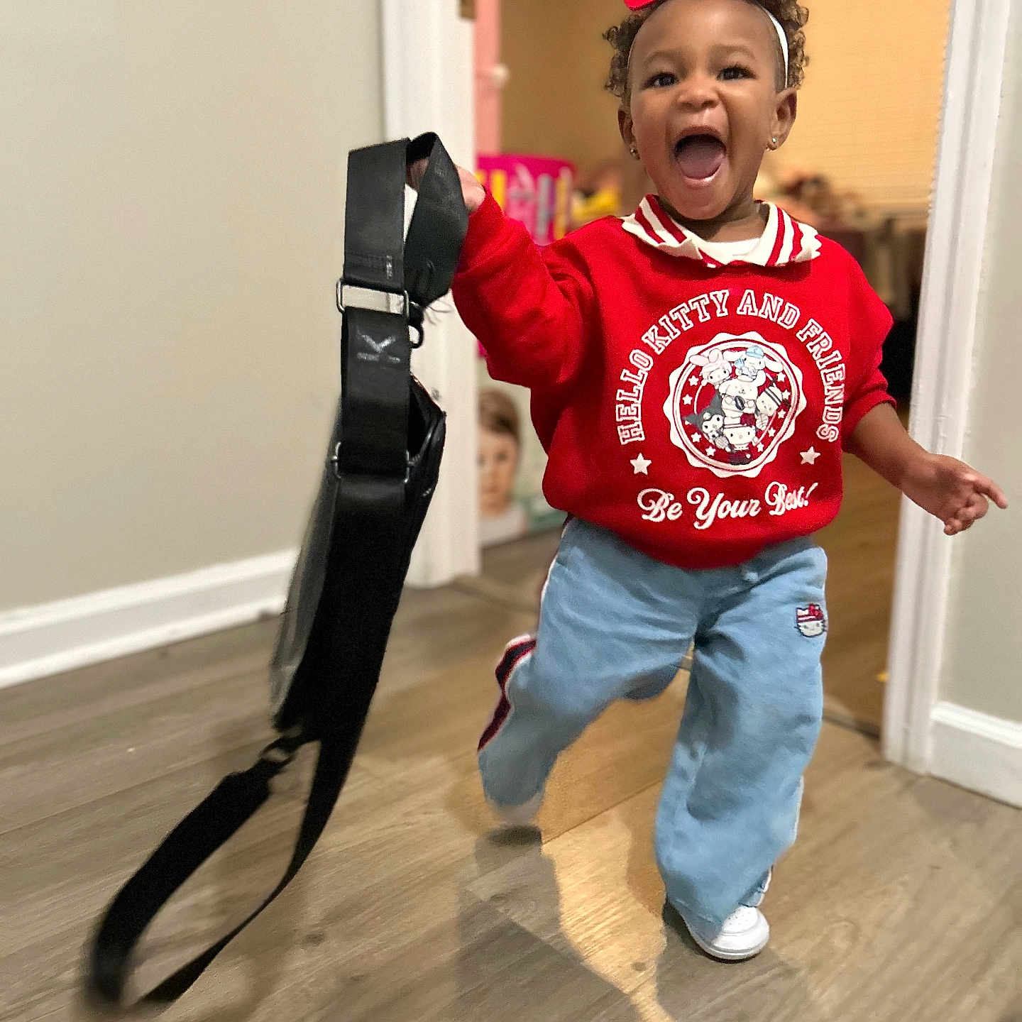 Khmyiah joined the competition — help win amazing prizes! child, toddler, indoor, running, red_sweatshirt, hello_kitty, blue_pants, white_shoes, headband, black_strap, smiling, happy, curly_hair, wooden_floor, doorway, wall, person, clothing, playful, motion_blur